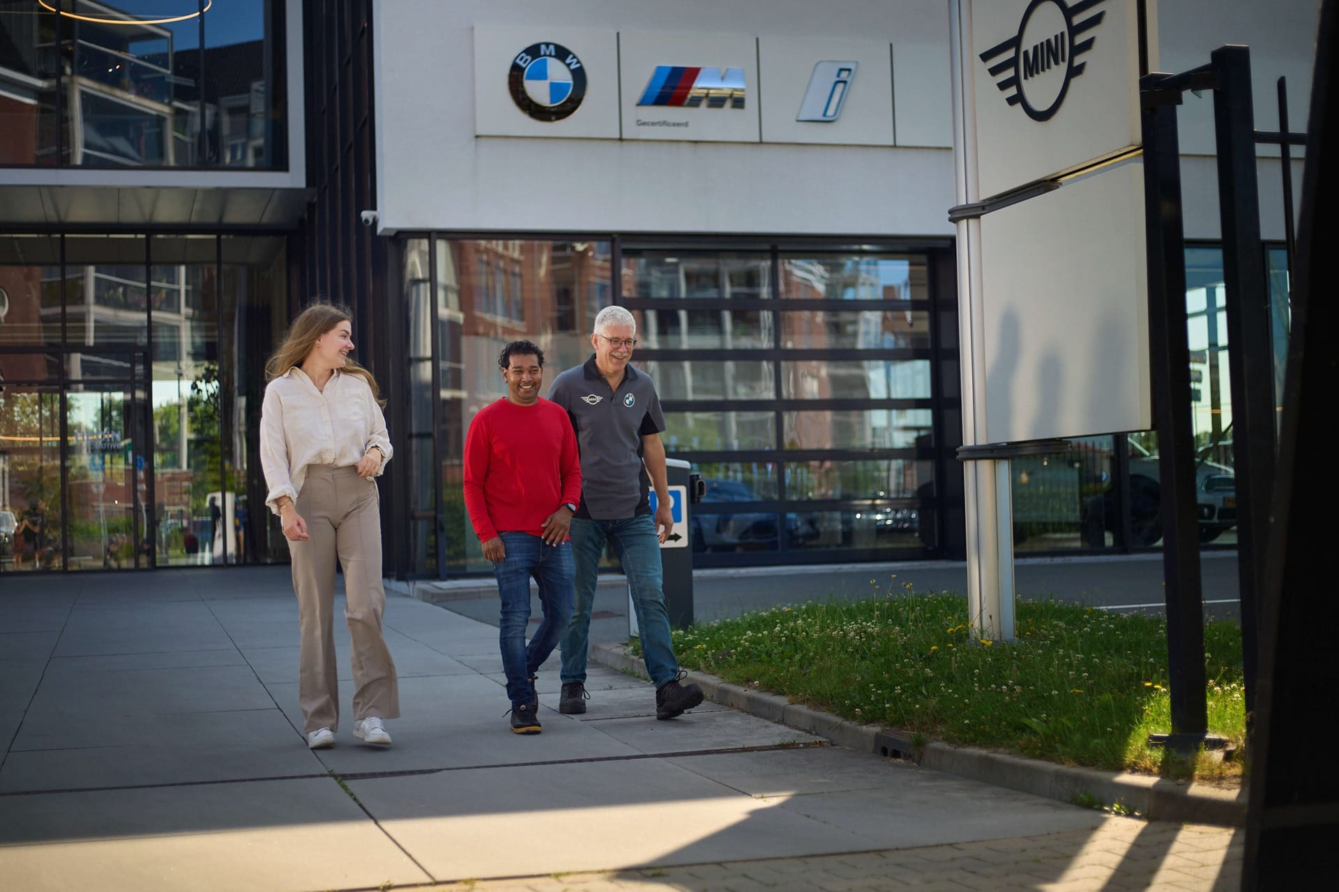 Mensen die uit een BMW dealer lopen.