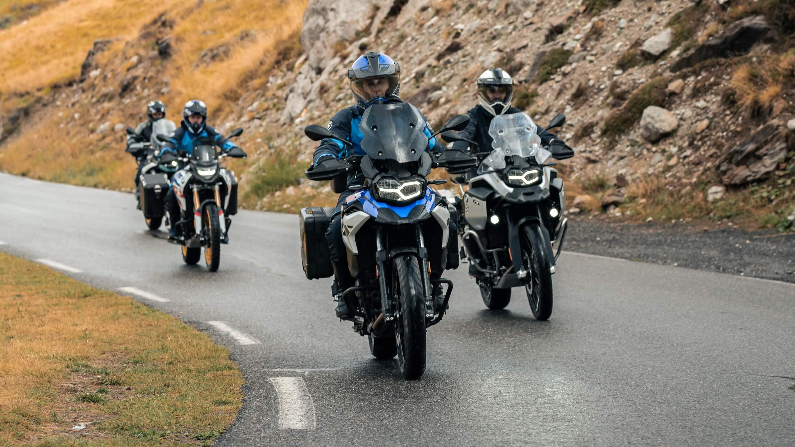 Meerdere BMW motorrijders in een landschap.